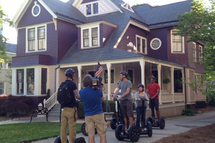 A guide explaining the history behind the mauve old style home to guests on Segways