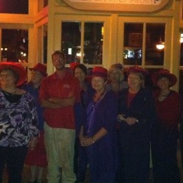 People enjoying a haunted walking tour. The women are wearing red hats.