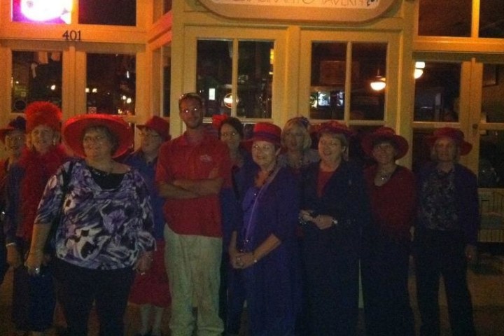 People enjoying a haunted walking tour. The women are wearing red hats.