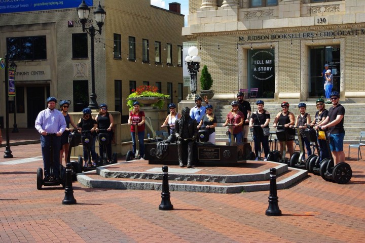Group of segway riders parked in front of historical statue in Charlotte